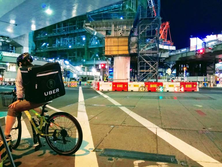 Uber delivery cyclist waiting at crossing in Shibuya