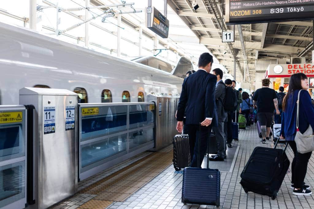 Train station platform with shinkansen and salaryman people with baggage